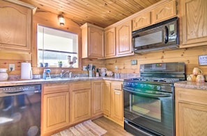 A kitchen with wooden cabinets, a stainless steel microwave, a stove, and a dishwasher. - Large Cabin w/ Deck Overlooking Norfork Lake! (Elizabeth)