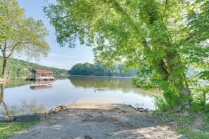 Ein Seeufer mit einem roten Gebäude, ruhigem Wasser und umliegender Bepflanzung.