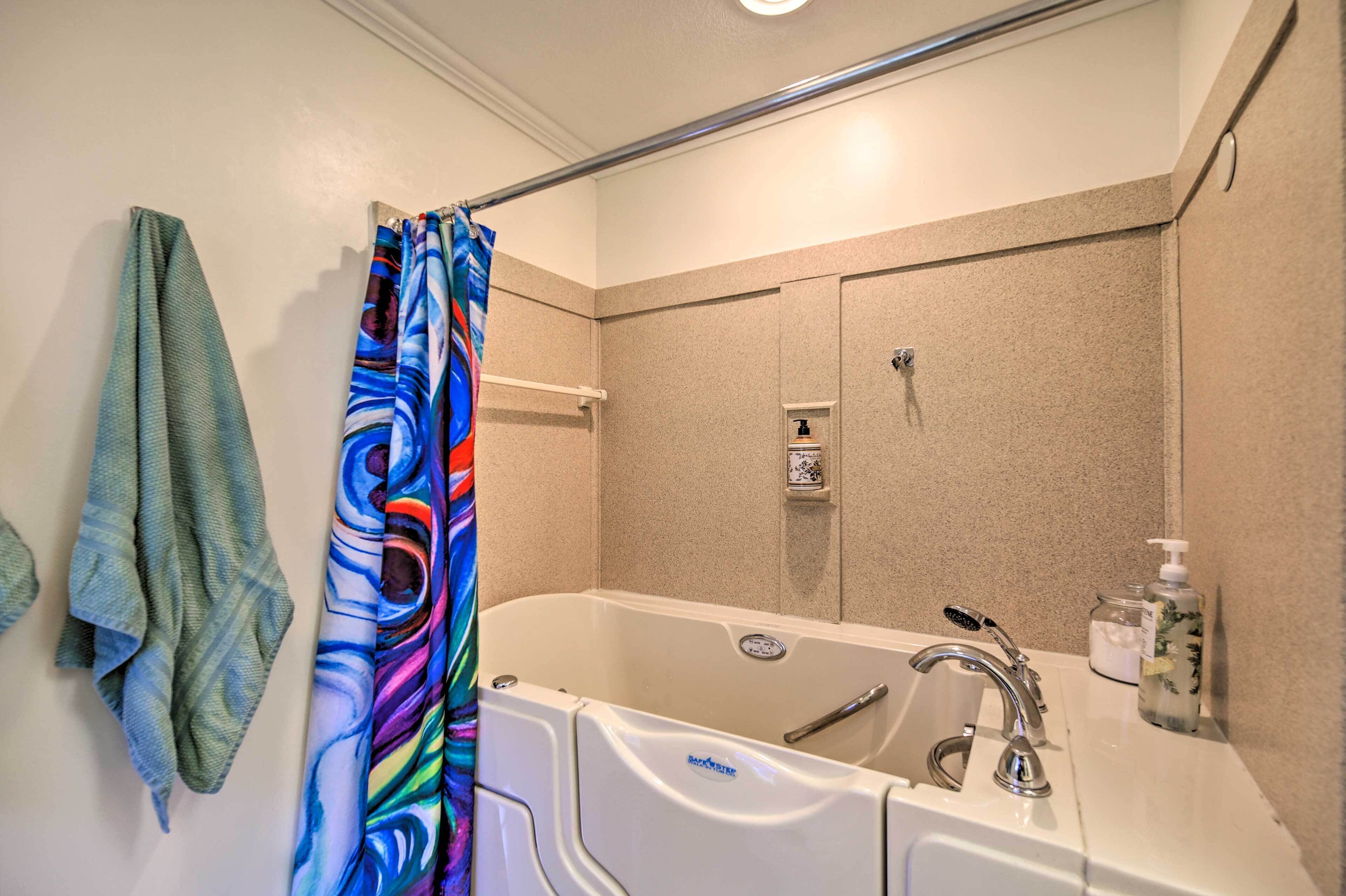 A bathroom with a bathtub, a towel rack, a shower curtain, a soap dispenser, and a hand soap bottle.