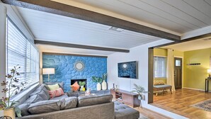 A modern living room with a stone-patterned accent wall, a sectional sofa, and a fireplace. - Tropical Palm Harbor Retreat With Lanai & Patio! (Palm Harbor)