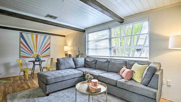A modern living room with a sectional sofa, a round coffee table, and a colorful abstract painting on the wall. - Tropical Palm Harbor Retreat With Lanai & Patio! (Palm Harbor)