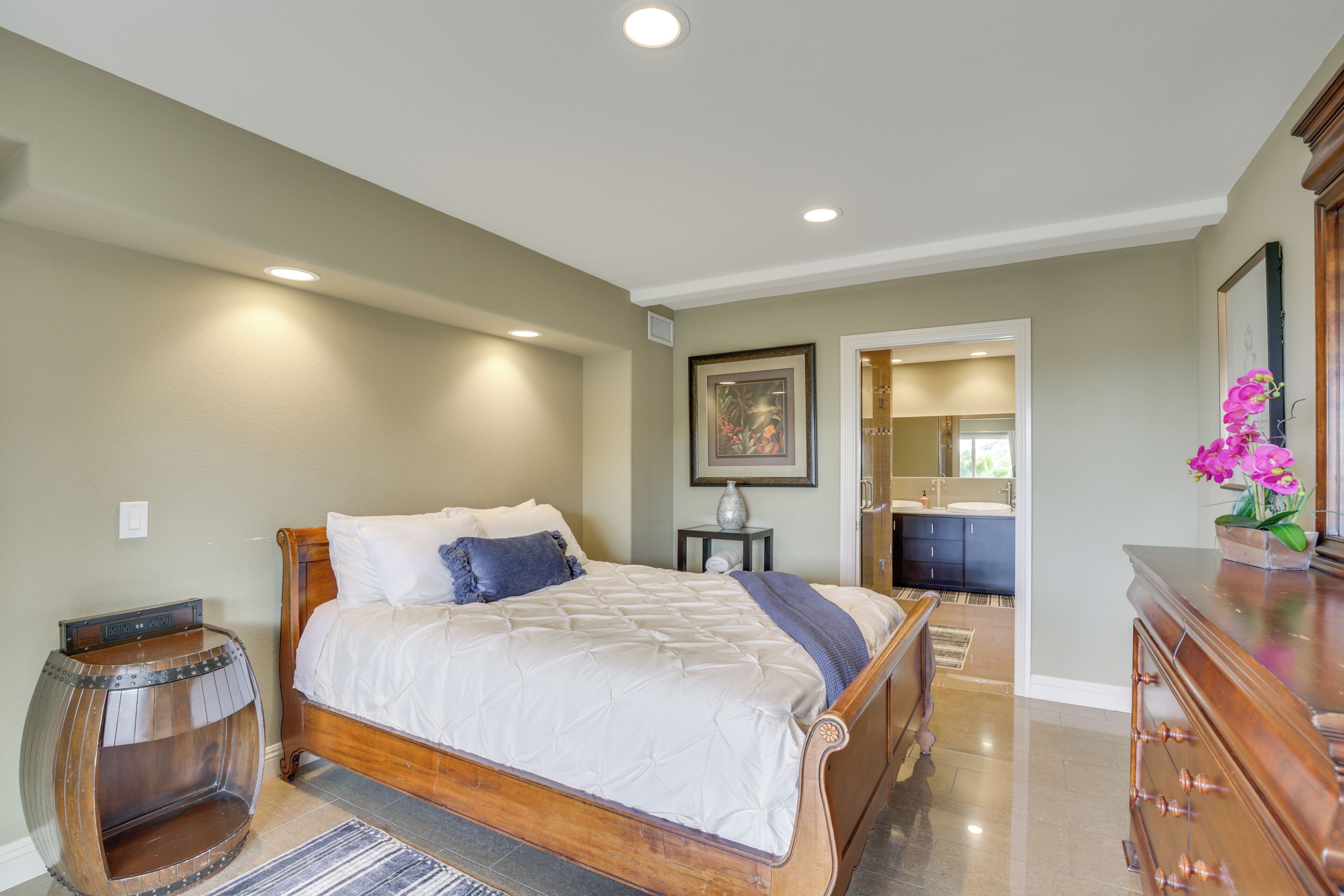 A bedroom with a wooden bed, a nightstand, a decorative barrel, and a dresser.