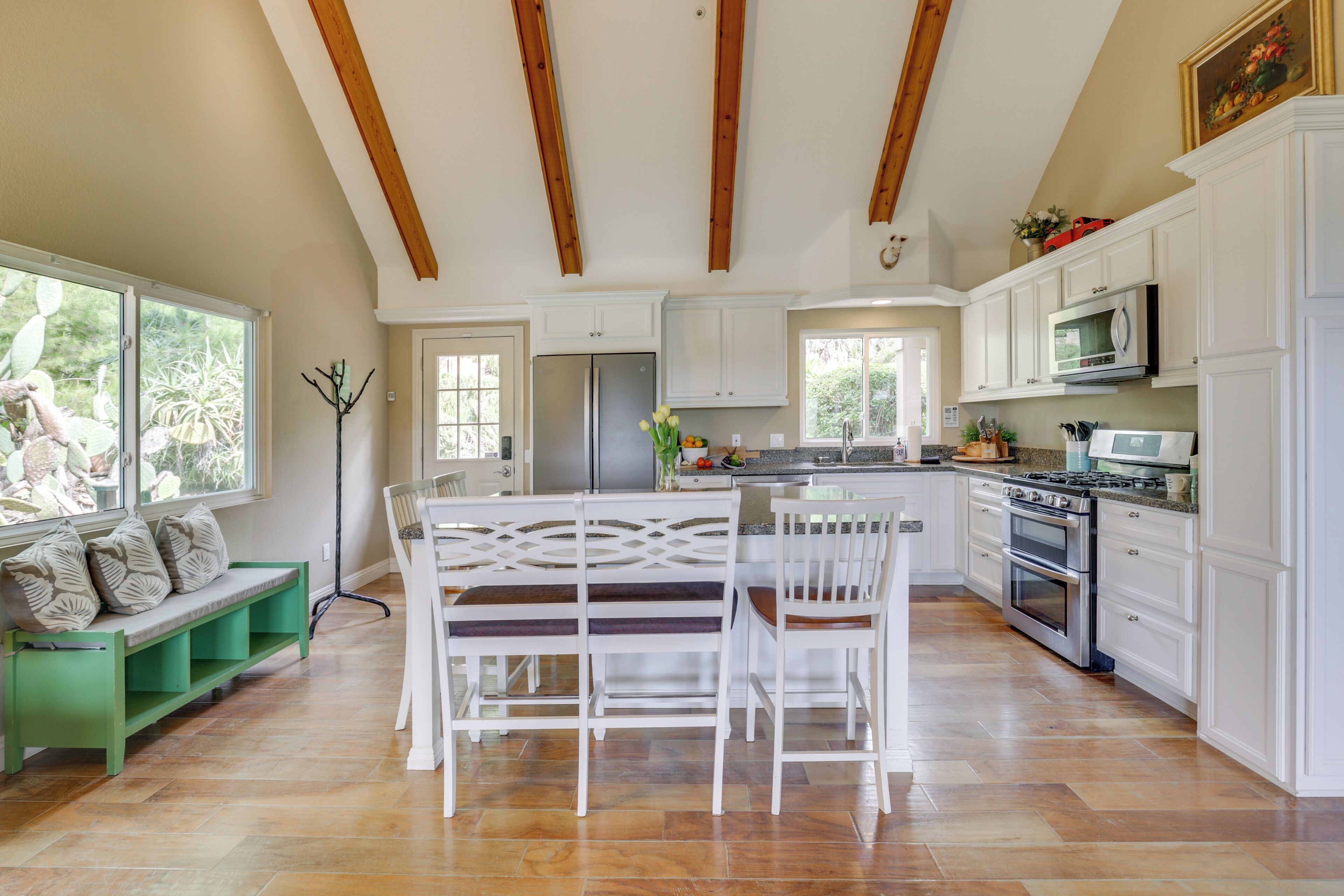 A spacious kitchen with white cabinets, a central island, and a dining area with a bench and chairs.