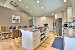 Cocina moderna con una isla central, electrodomésticos de acero inoxidable y un letrero que dice 'Our Happy Place'.