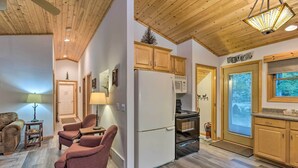 Une cuisine compacte avec des meubles en bois, un réfrigérateur, un four à micro-ondes et un four traditionnel. On y trouve un coin salon avec deux chaises et une table, ainsi qu’une porte portant l’inscription « RIVIÈRE ».