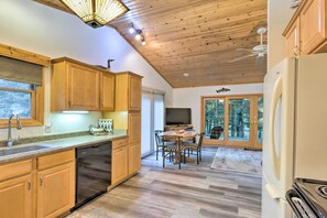 Una cocina moderna con armarios de madera, lavavajillas, refrigerador y un comedor con mesa y sillas.