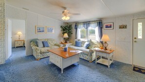 A cozy room with a floral-patterned sofa, a wooden coffee table, and a ceiling fan.
