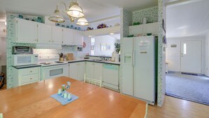 A kitchen with white cabinets, a wooden dining table, and a refrigerator.