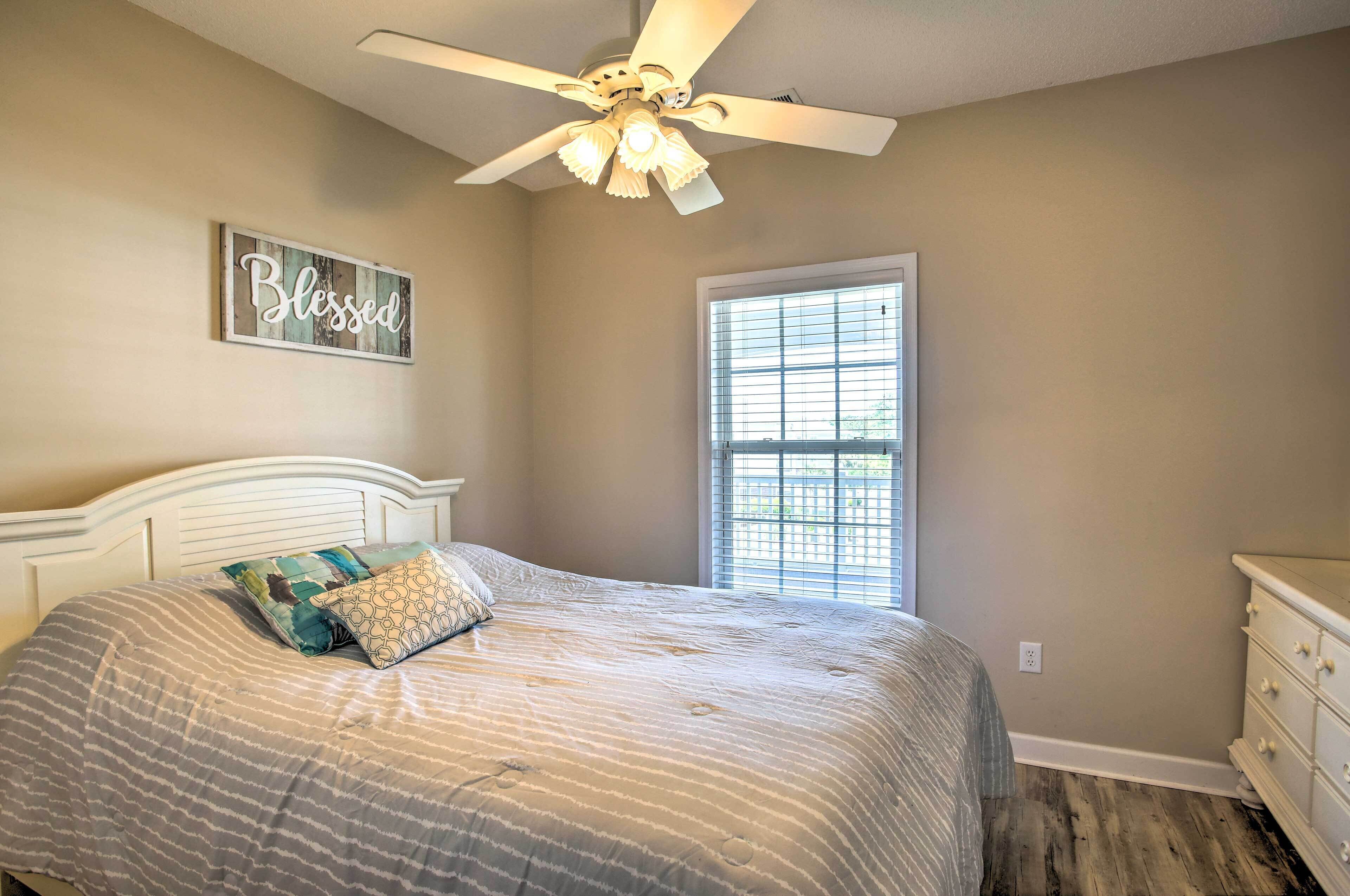 A bedroom with a bed, a ceiling fan, a window, and a dresser.