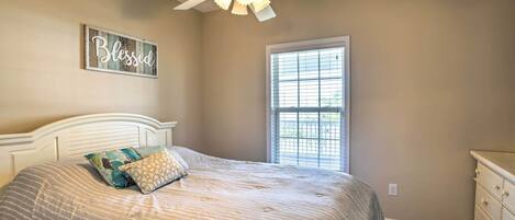A bedroom with a bed, a ceiling fan, a window, and a dresser.