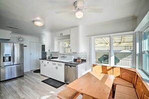 A modern kitchen with white cabinets, stainless steel appliances, and a wooden dining table with benches.