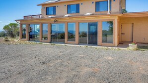 Une maison à deux étages avec de grandes fenêtres en verre, un balcon et une allée gravillonnée.
