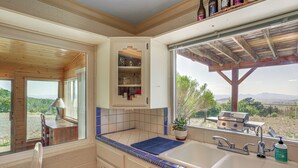 Une cuisine dotée d’une grande fenêtre, de meubles en bois et offrant une vue sur l’extérieur.