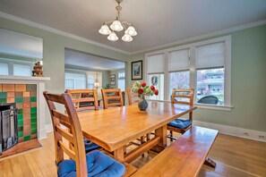 A dining area with a wooden table, blue upholstered chairs, a vase with flowers, and a fireplace. - Peaceful Wine Country Getaway - Walk to Downtown! (Walla Walla)