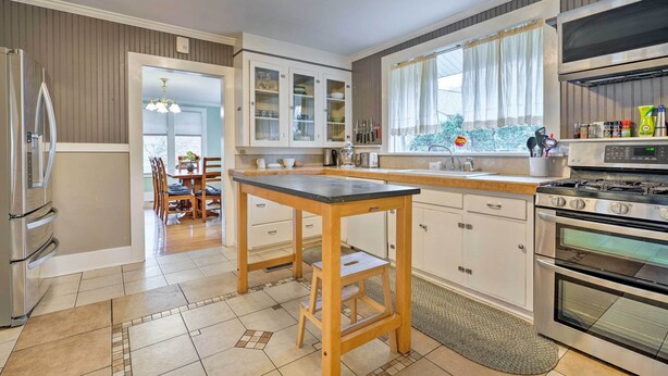 A modern kitchen with a central island, stainless steel appliances, and a dining area with a view. - Peaceful Wine Country Getaway - Walk to Downtown! (Walla Walla)