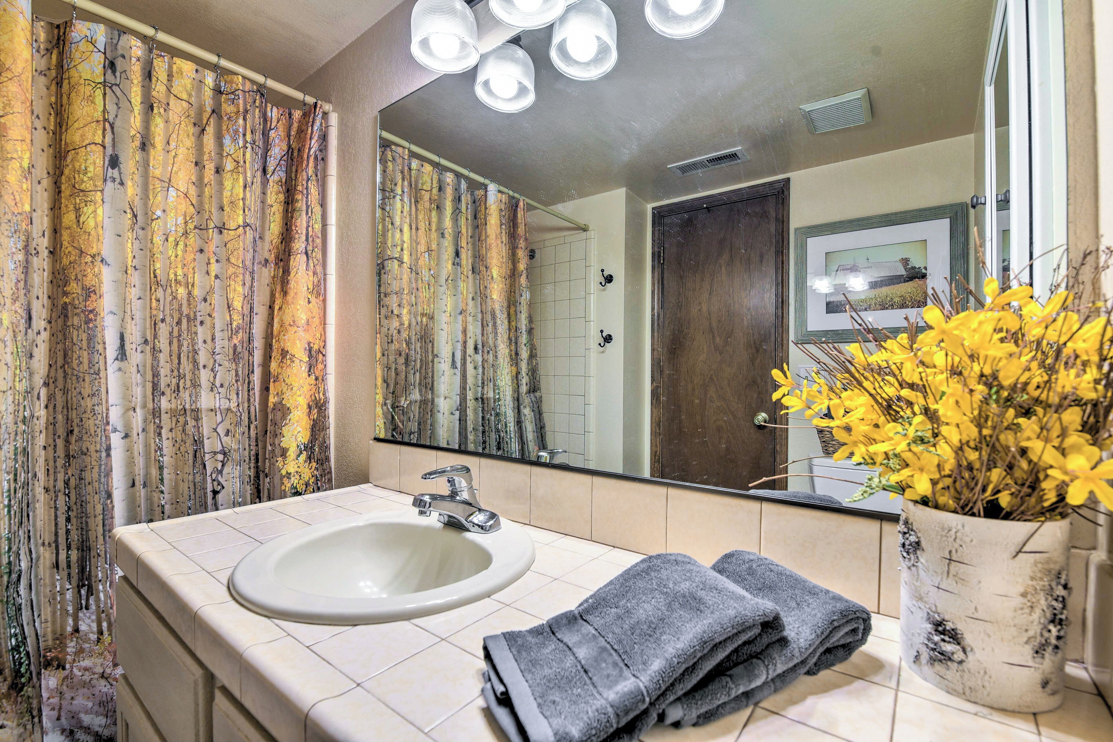 A bathroom with a sink, mirror, and a potted plant.