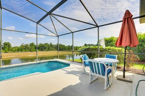 A covered outdoor area with a pool, chairs, and a view of a lake.