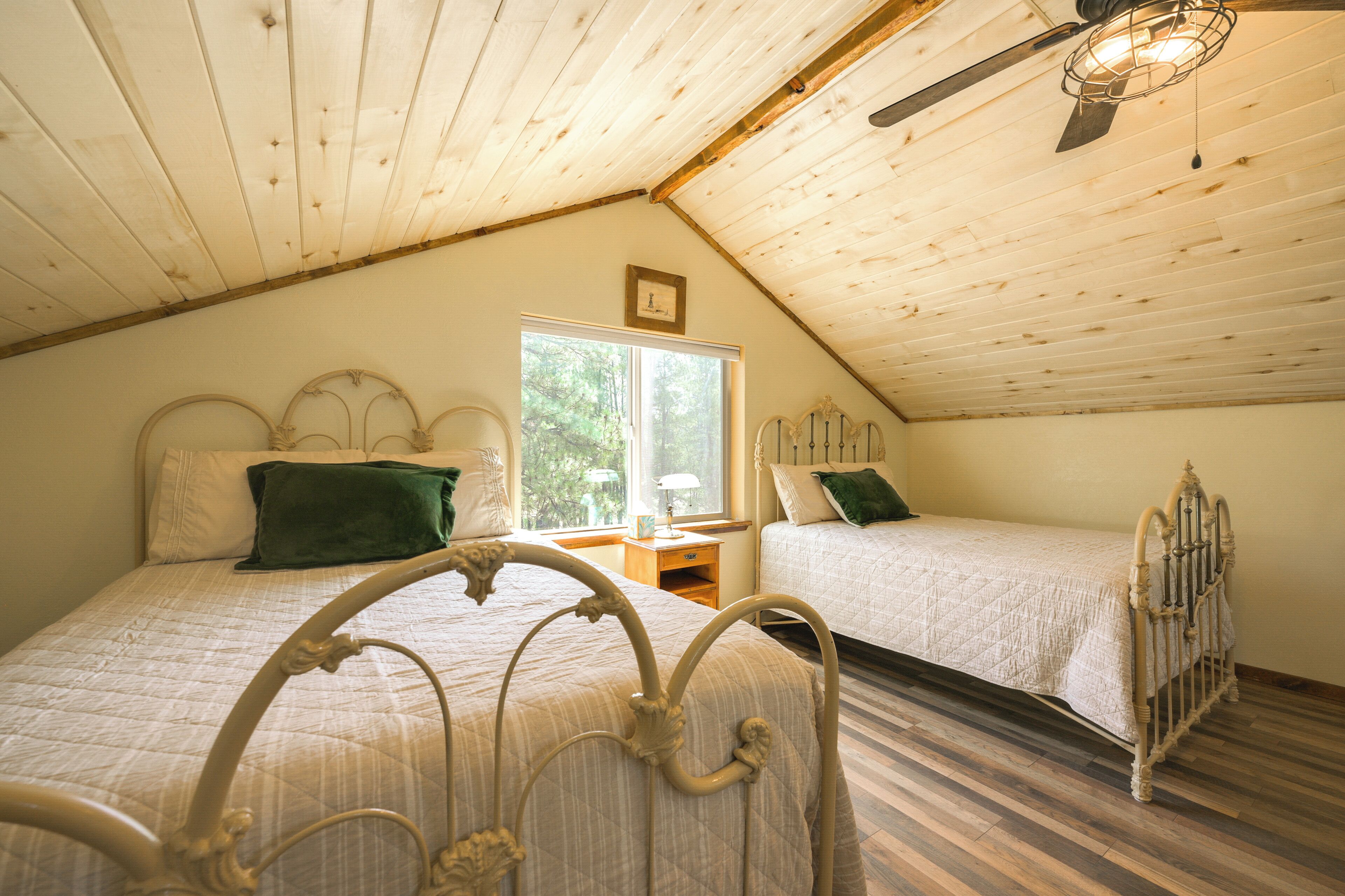 Een slaapkamer met twee bedden, houten plafond en een raam.