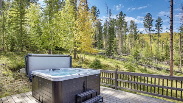 Ein Whirlpool auf einer Holzterrasse mit Blick auf einen Wald.
