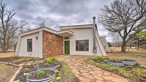 A modern house with a stone facade, a green door, and a stone pathway leading to the entrance.