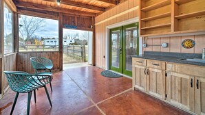 A rustic kitchen with wooden cabinets, a green door, and a patio area with chairs.