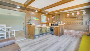 A modern kitchen with wooden cabinets, a brick accent wall, and a clock displaying different times. - Location! Home w/ Pool 1 Min to Mcculloch Blvd (Lake Havasu City)