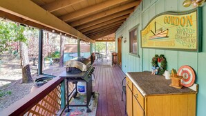 A covered outdoor area with a grill, a wooden counter, and a sign that reads "Gordon Key West Shrimp Distributors." - Relax Fireside: Rustic Gem 2 Mi to Rainbow Lake! (Lakeside)