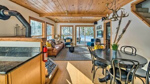 Un intérieur de chalet chaleureux comprenant un coin repas, un salon avec un canapé et une cheminée.