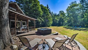 Une terrasse avec mobilier d’extérieur, un jacuzzi et une vue sur une zone boisée.