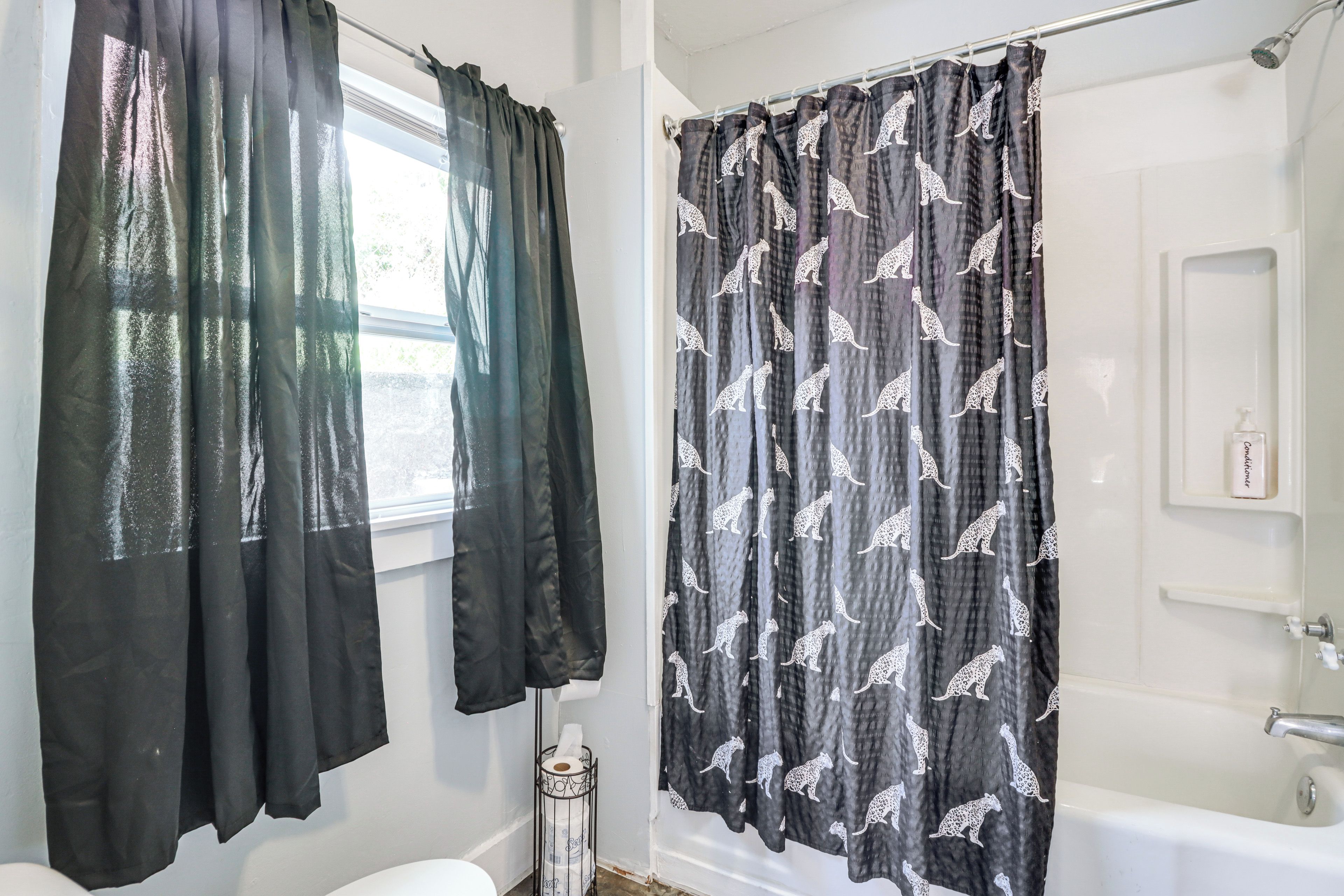 Un baño con inodoro, ducha y cortina estampada de leopardo.