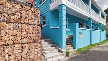 Ein zweistöckiges Gebäude mit einer Steinsäule links und einer blauen Fassade mit weißem Zierdekor.