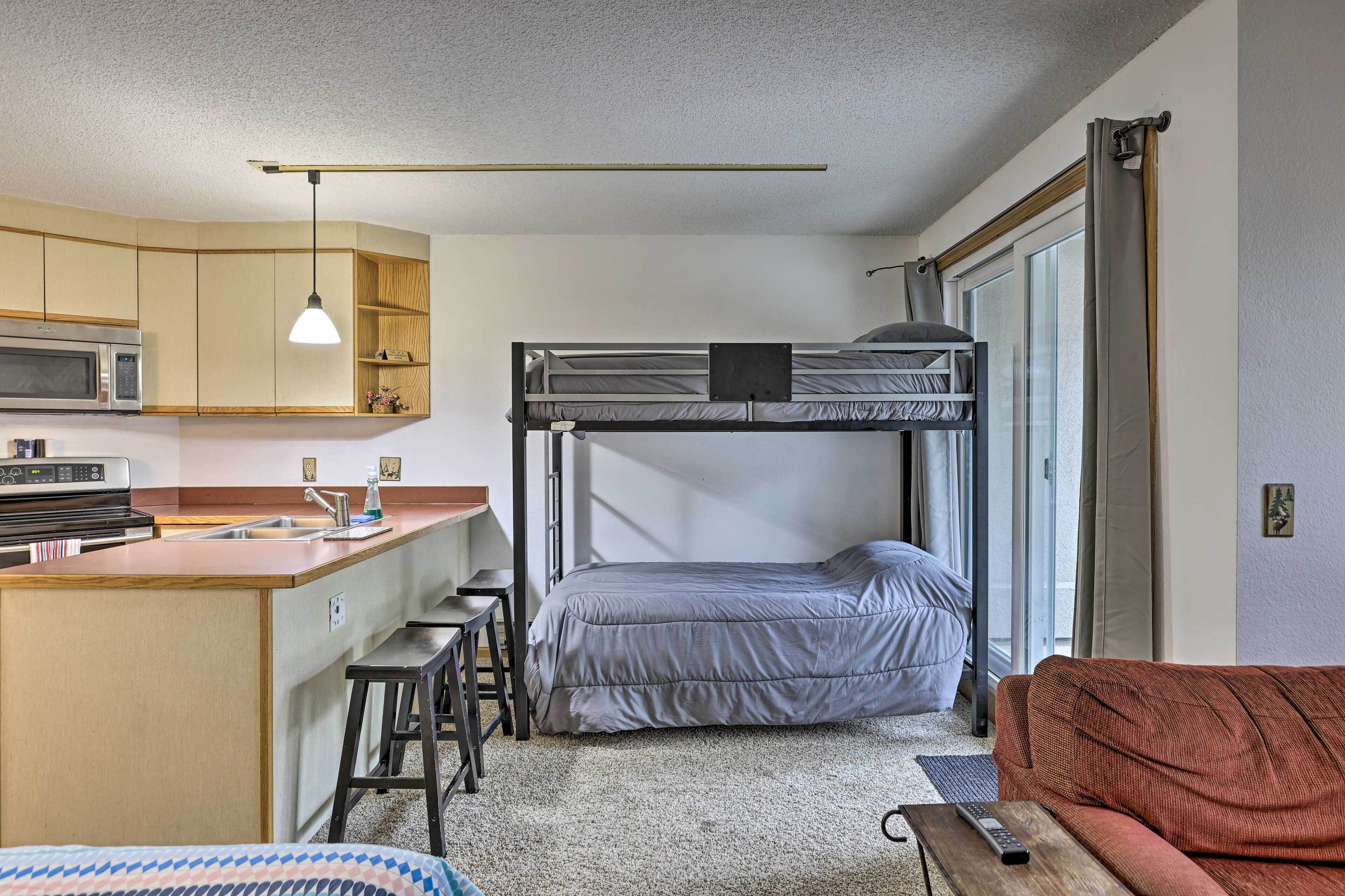 Ein kompaktes Hotelzimmer mit Etagenbett, Küchenzeile und Schlafsofa.