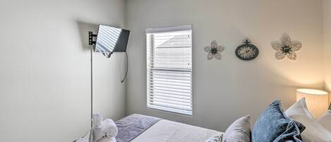 A bedroom with a bed, a desk, a lamp, and a window with blinds.