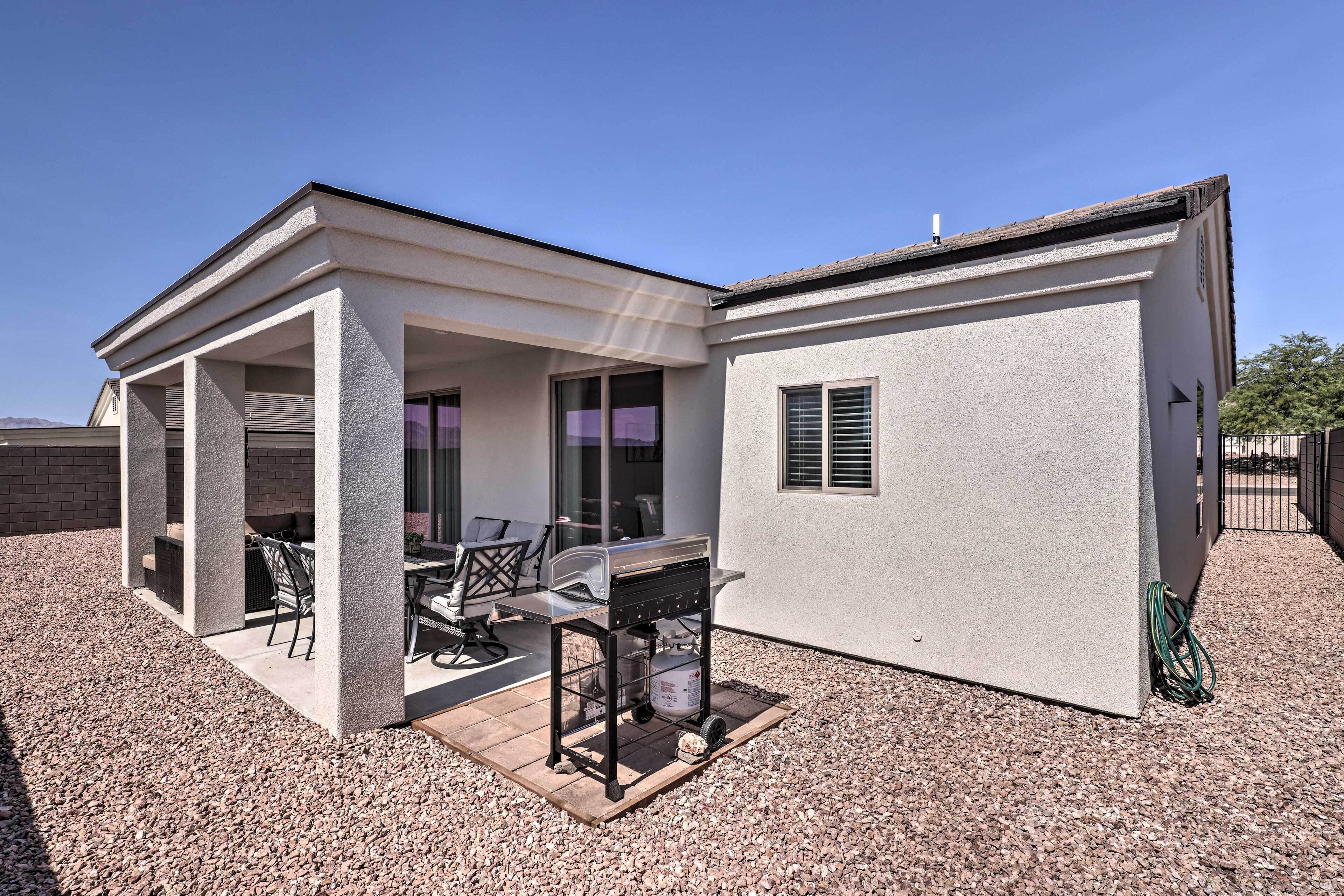 A two-story house with a patio area featuring a grill and outdoor seating.