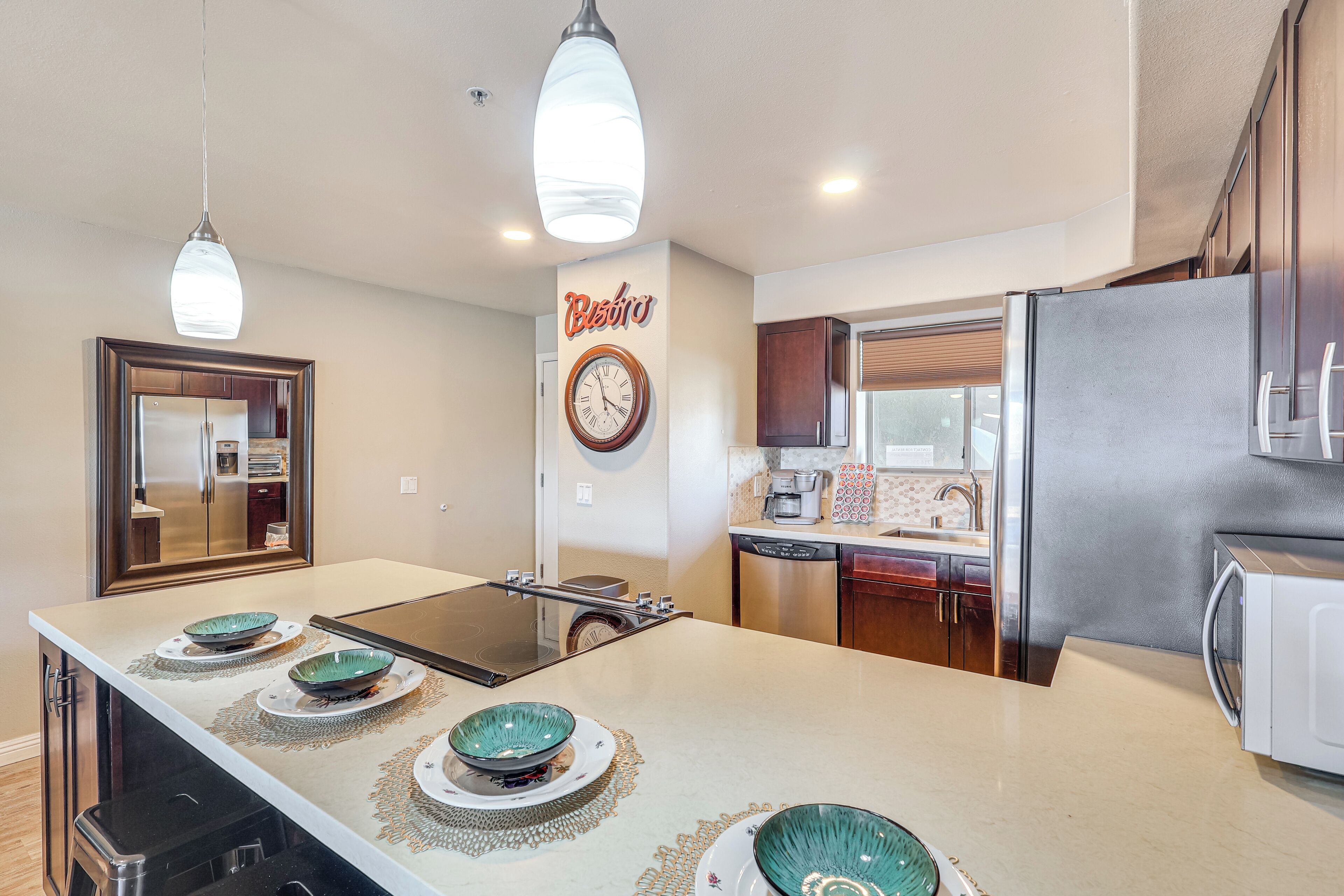 A modern kitchen with a central island, stainless steel appliances, and a clock on the wall.