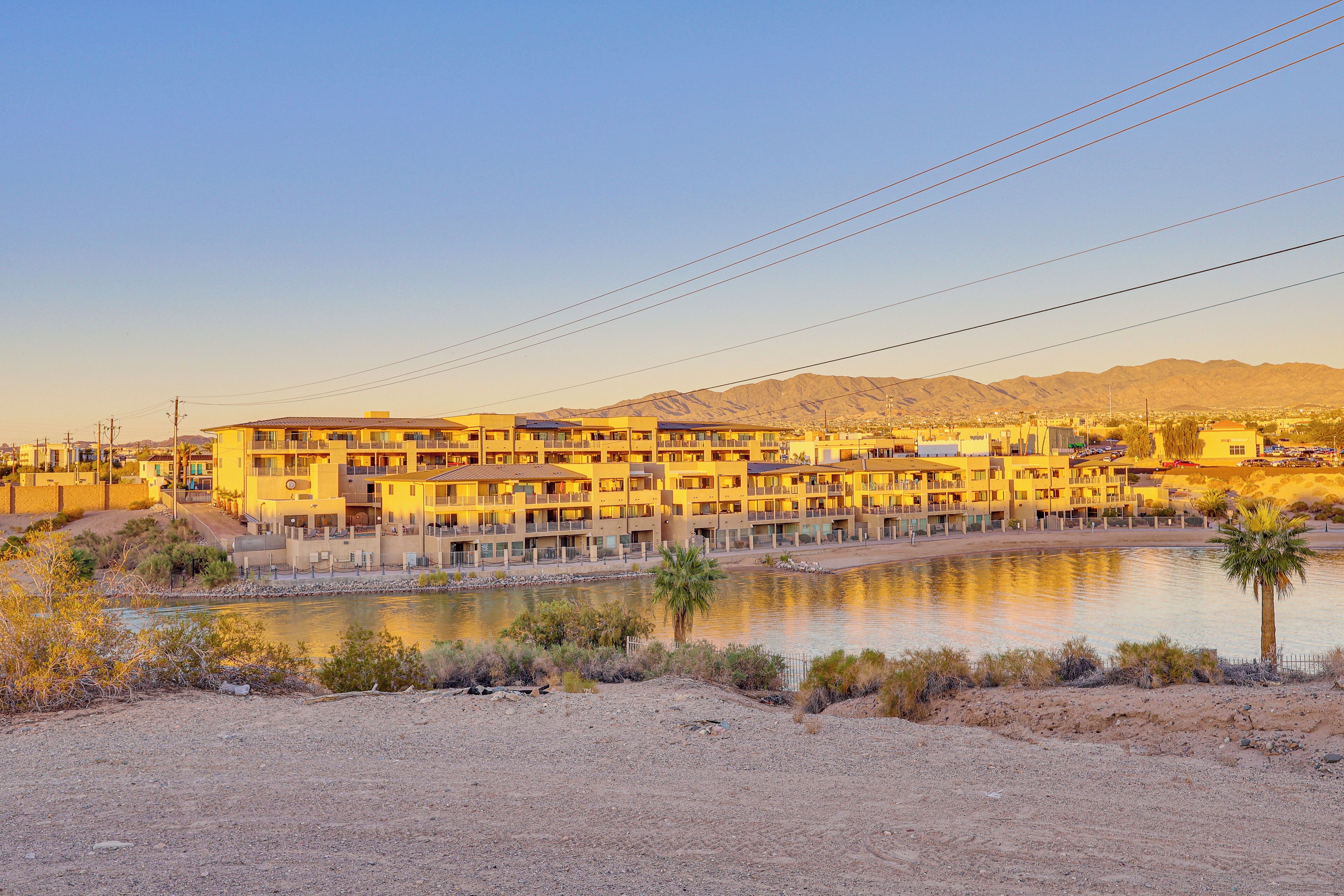 A multi-story hotel with balconies, a pool, and a desert landscape in the background.