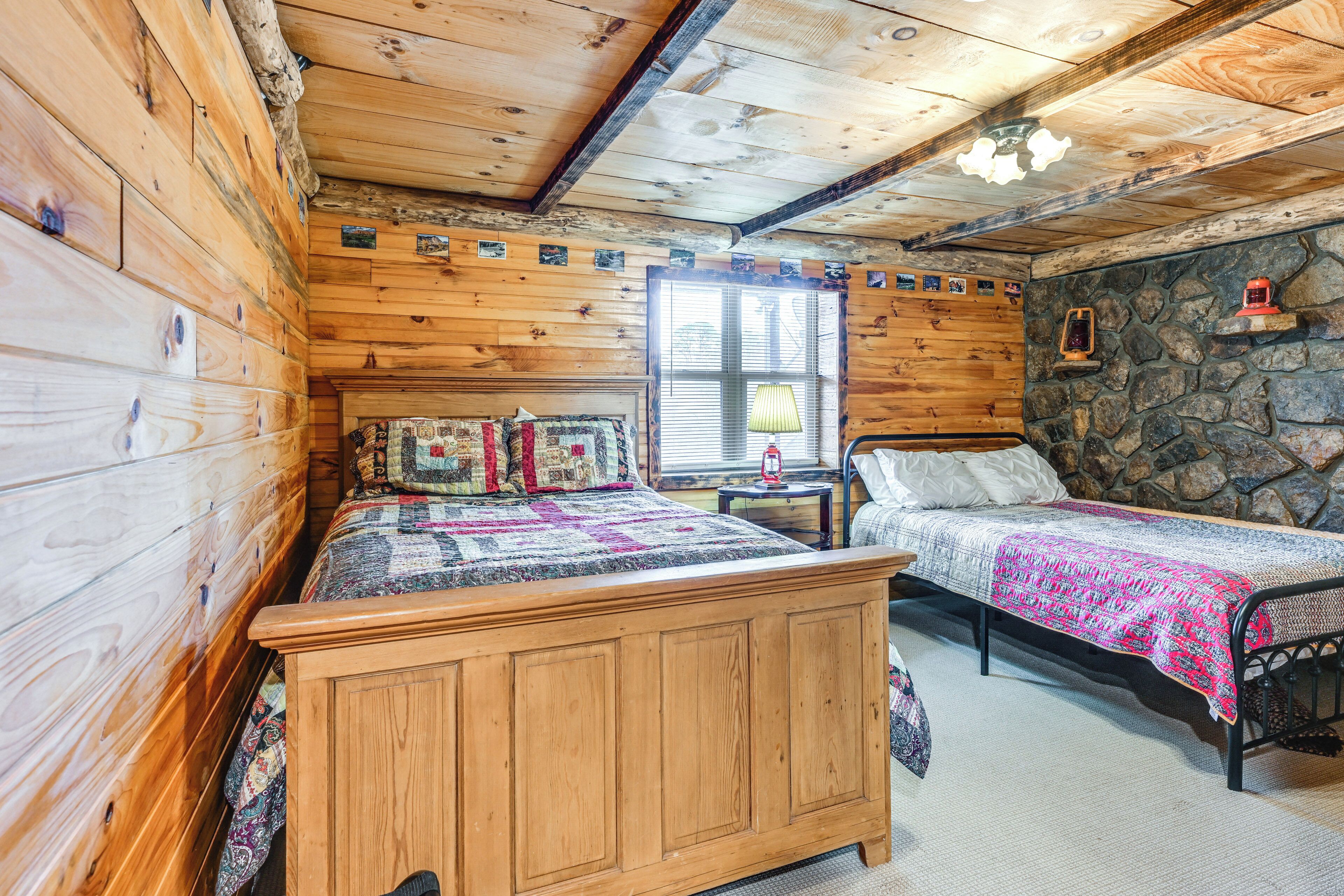 Un dormitorio acogedor de cabaña con una cama de madera, una cama individual y una pared de piedra.