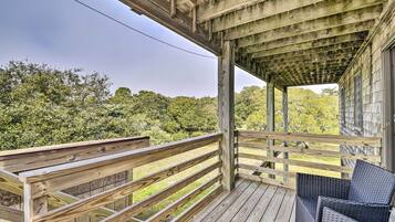 Enjoy the serene views from this outdoor deck with a wicker chair and simple railing.
