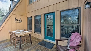 A wooden deck with a dining table and chairs, a teal door, and a bench with a blanket. - 1 Mi to Skiing: Beech Mountain Condo w/ Fireplace! (Banner Elk)