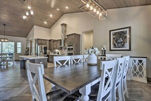 A spacious kitchen with wooden cabinets, a large island, and a dining area with white chairs and a wooden table. - Stylish Show Low House w/ Expansive Deck! (Show Low)