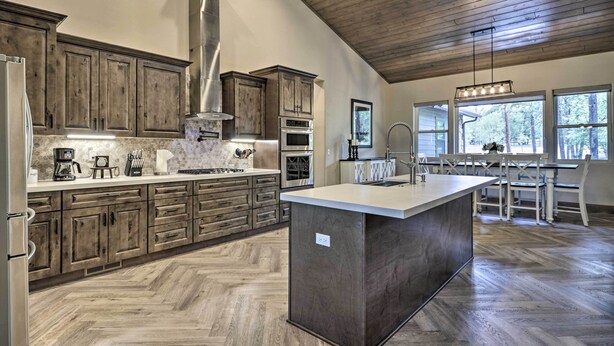 A spacious kitchen with wooden cabinets, a large island, and a herringbone floor pattern. - Stylish Show Low House w/ Expansive Deck! (Show Low)