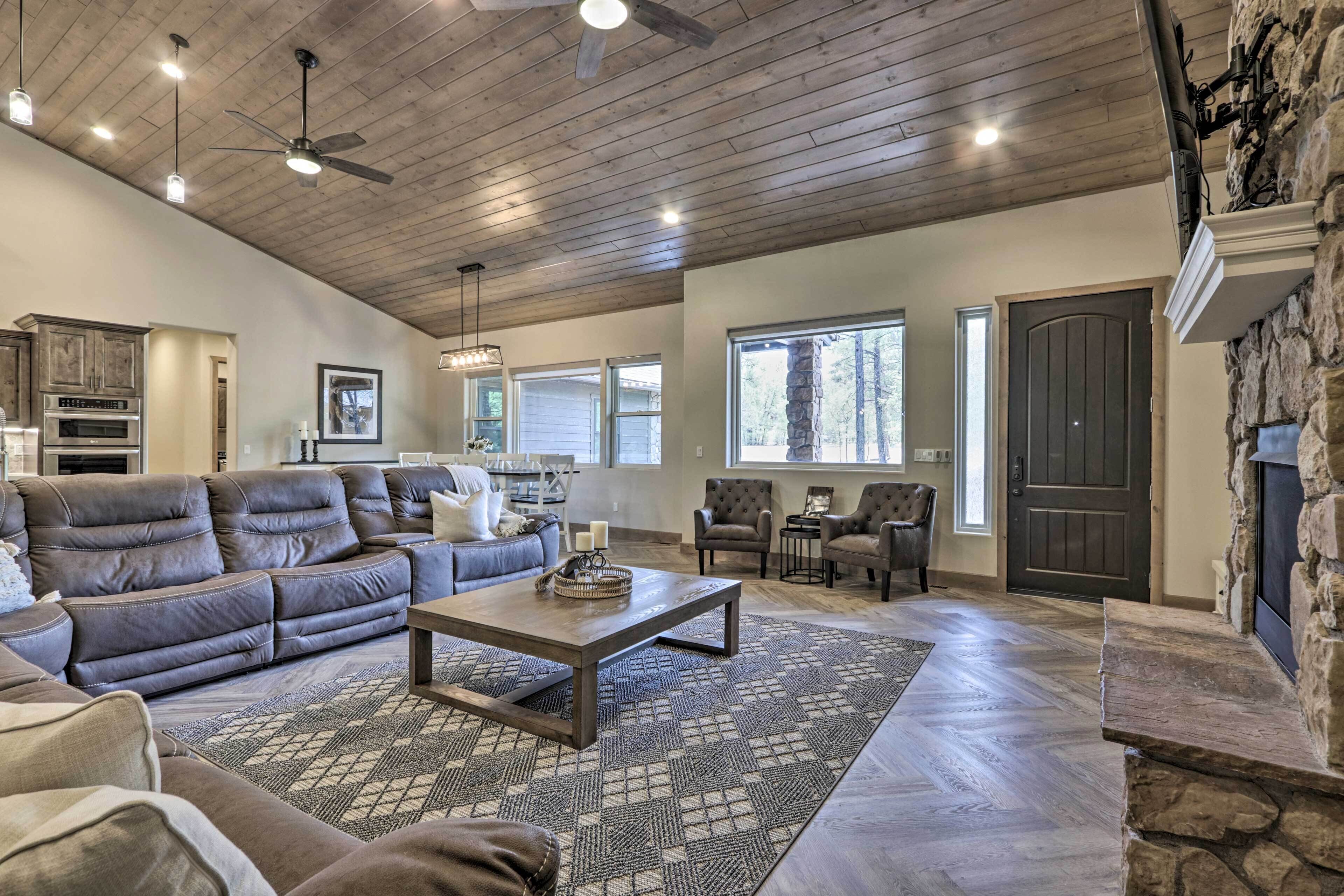A spacious living room with a stone fireplace, a large sofa, and a dining area.