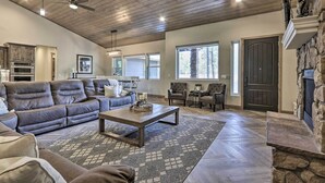 A spacious living room with a stone fireplace, a large sofa, and a dining area. - Stylish Show Low House w/ Expansive Deck! (Show Low)