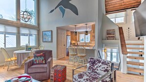 A spacious living area with a high ceiling, wooden flooring, and a view of the kitchen through an open door. - Spacious Village of Loon Home < 1 Mi to Ski Slopes (Lincoln)