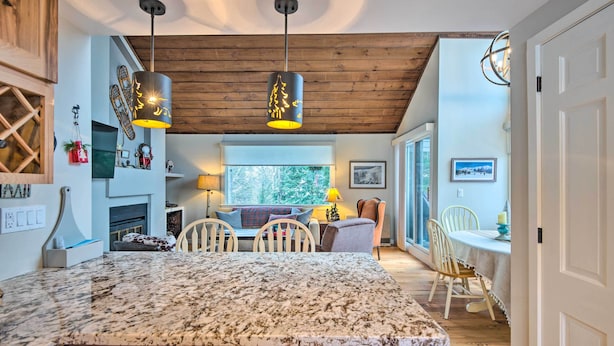 A modern kitchen with a large granite countertop, wooden ceiling beams, pendant lights, and a view to the dining area. - Spacious Village of Loon Home < 1 Mi to Ski Slopes (Lincoln)