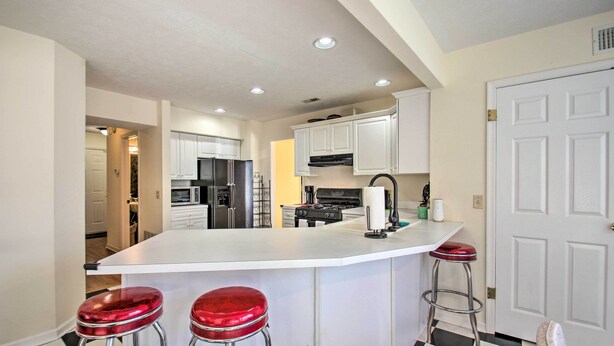 A kitchen with a central island, white cabinets, and a black and white checkered floor. - Central Harrisonburg Home w/ Fenced-in Yard! (Harrisonburg)