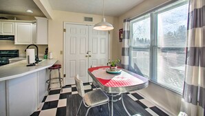 A kitchen with a dining area, featuring a checkered floor, white cabinets, a bar counter, and a hanging light fixture. - Central Harrisonburg Home w/ Fenced-in Yard! (Harrisonburg)