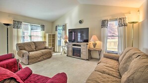 A living room with a beige sofa, a red sofa, a TV, and a fireplace. - Central Harrisonburg Home w/ Fenced-in Yard! (Harrisonburg)