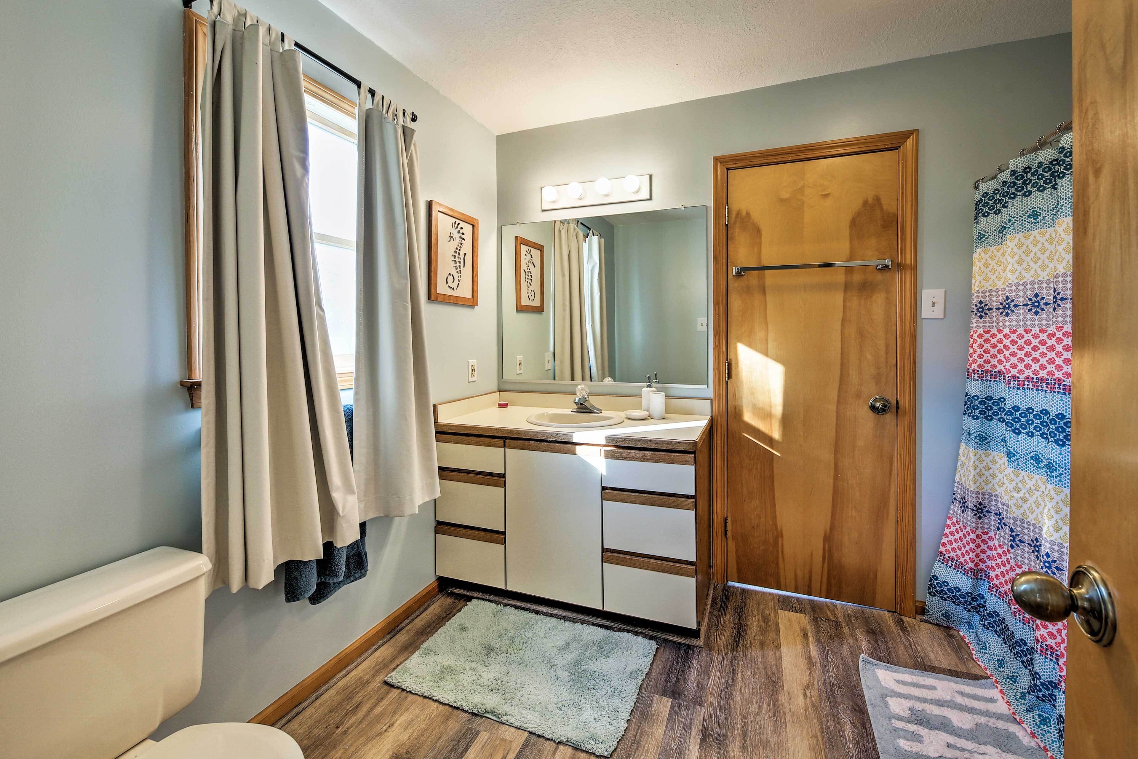 A bathroom with a toilet, sink, mirror, and wooden door.