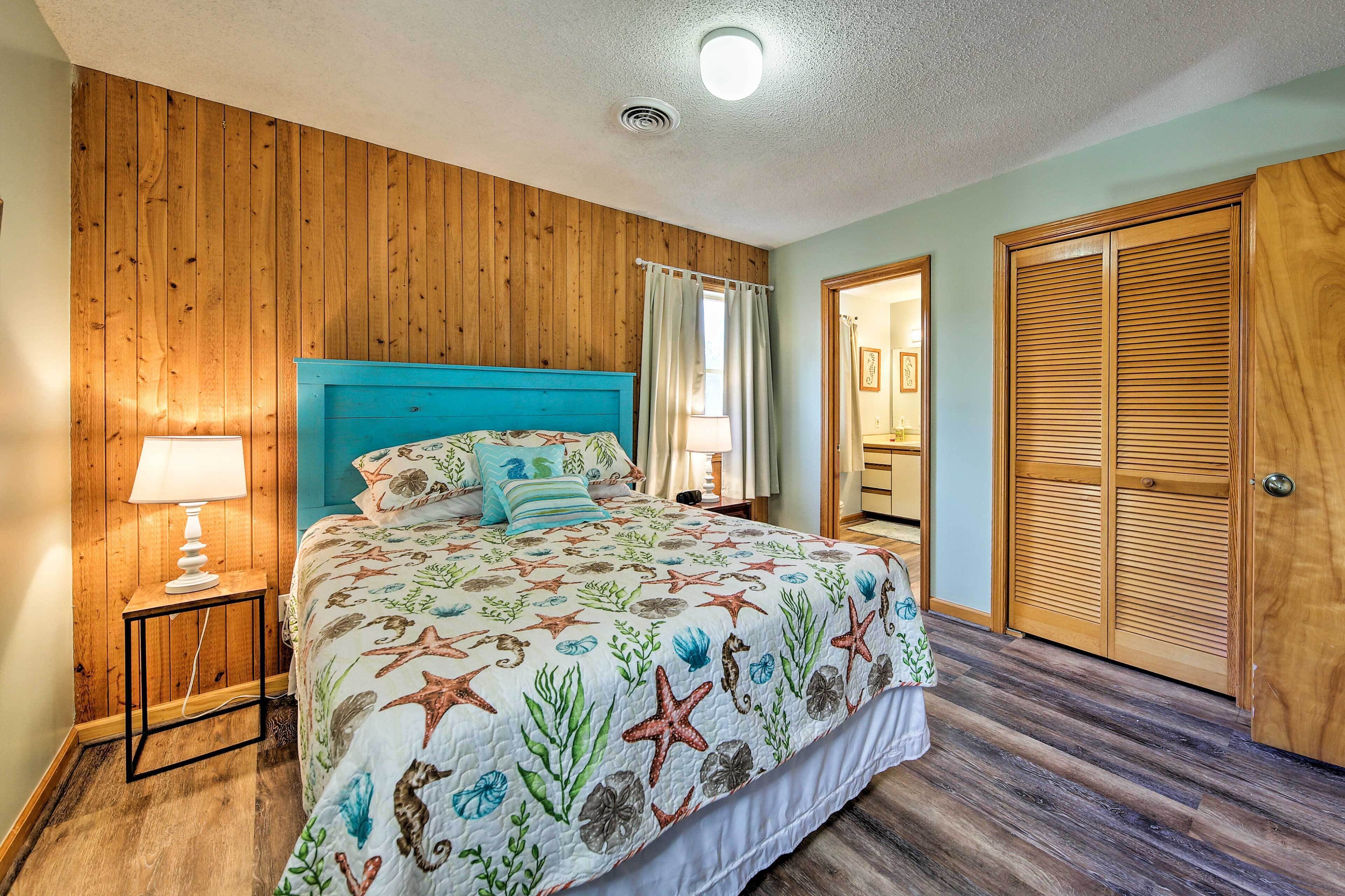 A bedroom with a wooden headboard, a bed with a starfish-themed bedspread, a nightstand with a lamp, and a wooden wardrobe.